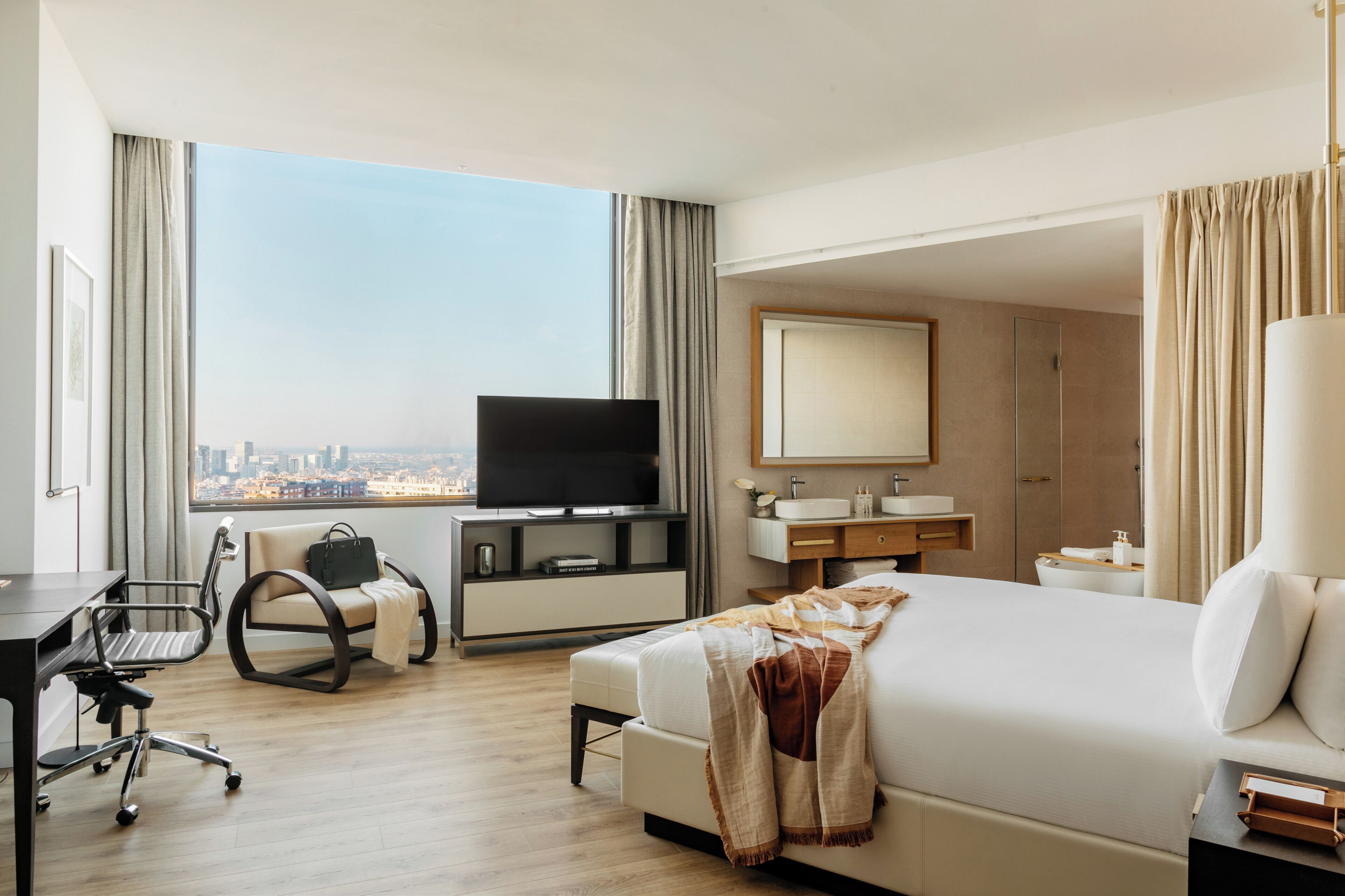 Een hotelkamer met een bed, televisie, bureau, stoel en een badkamer.