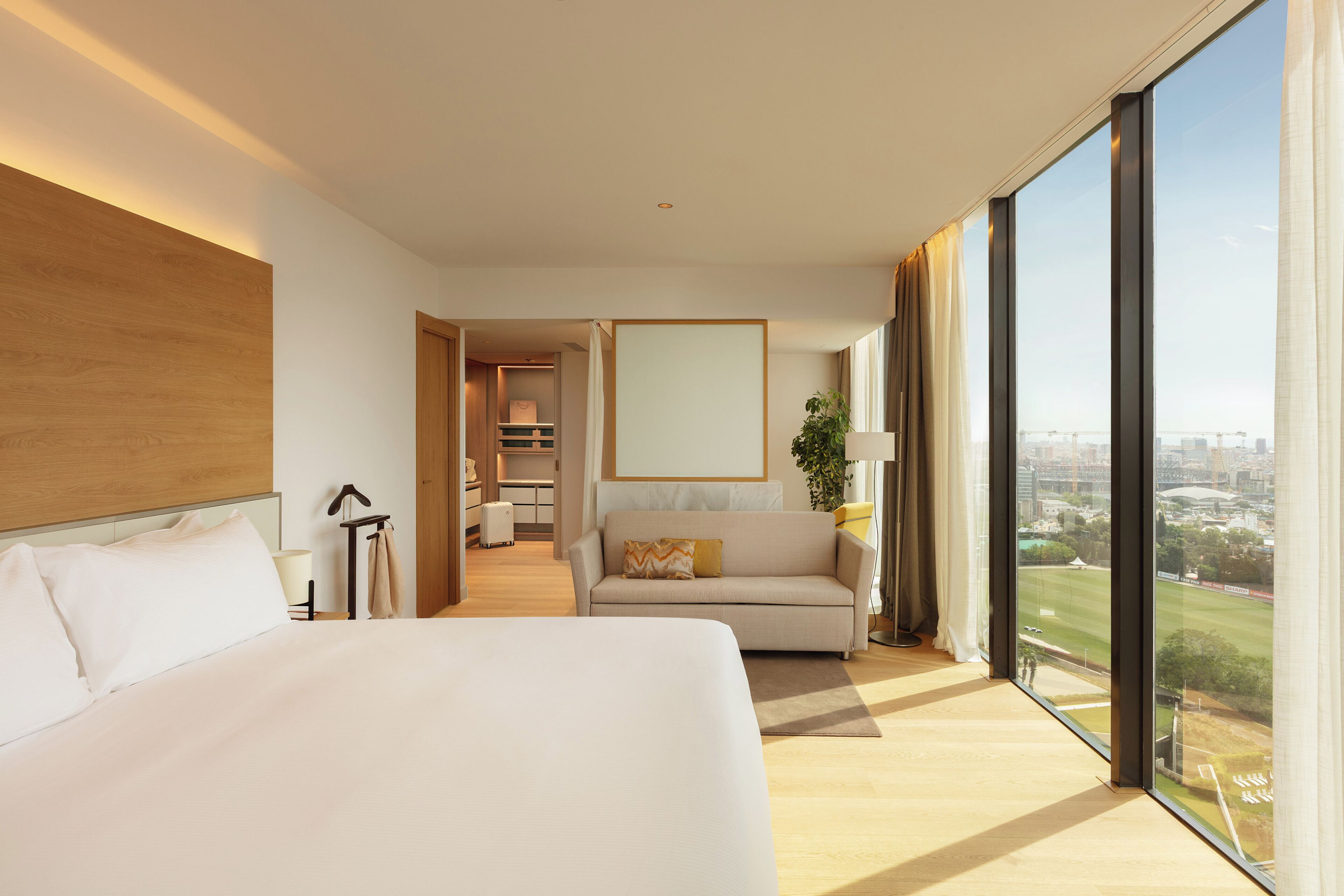 Habitación de hotel con una cama grande, un sofá, vistas de la ciudad y un área de comedor separada.