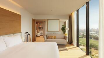 Habitación de hotel con una cama grande, un sofá, vistas de la ciudad y un área de comedor separada.