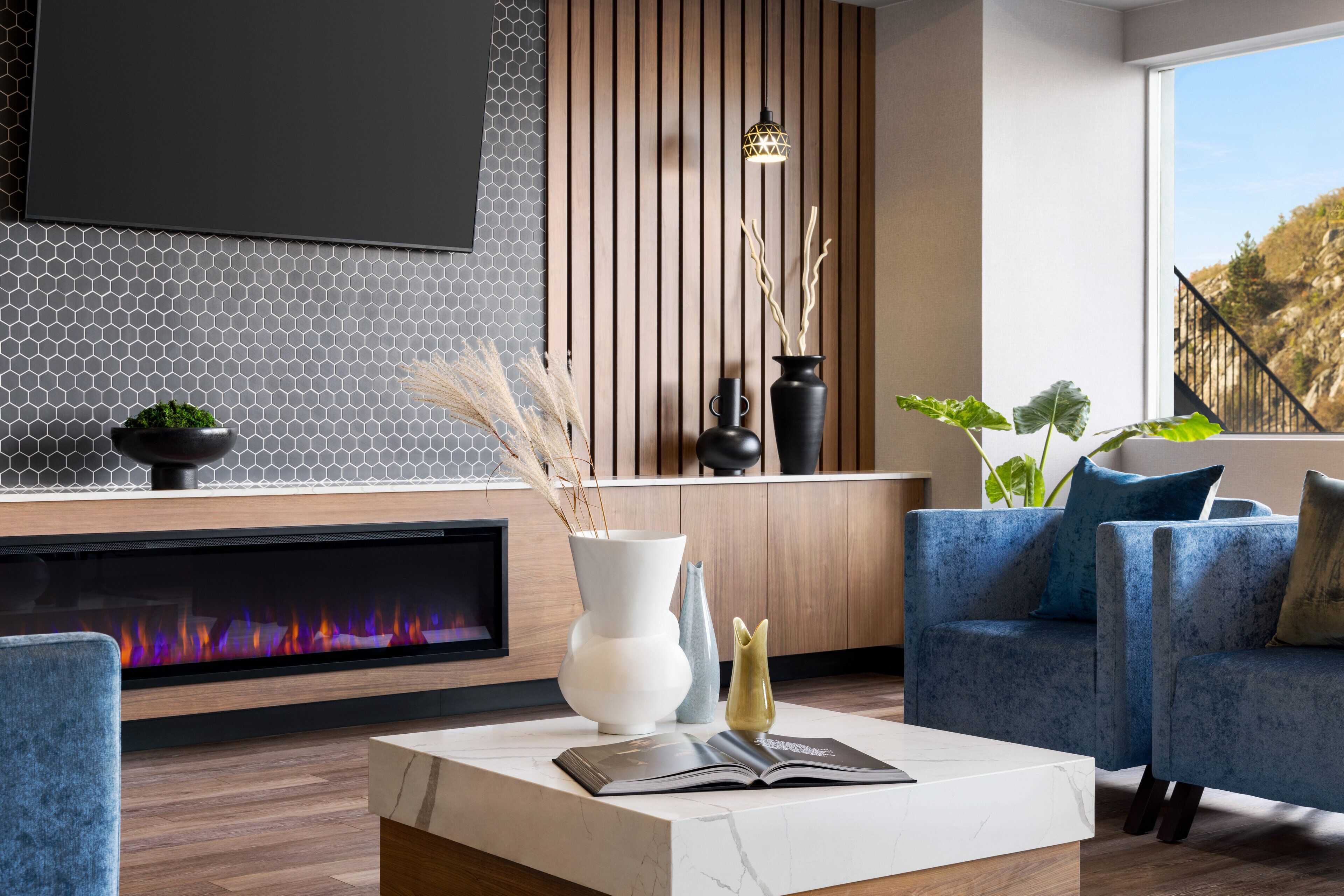 Un salon moderne avec une cheminée, des canapés bleus et une table basse sur laquelle repose un livre.