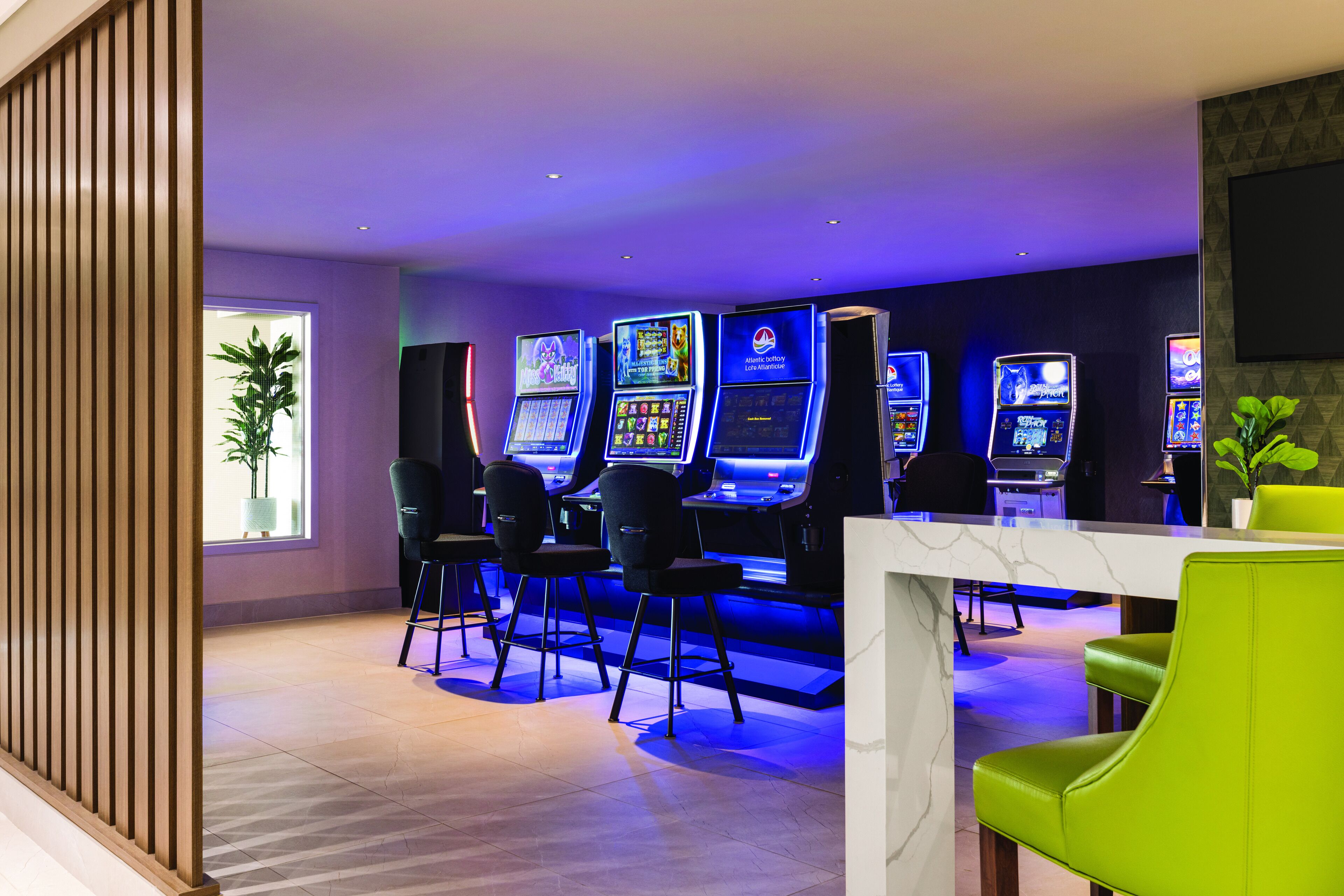 A gaming area with multiple slot machines, bar stools, and a table.