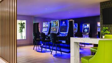 A gaming area with multiple slot machines, bar stools, and a table.
