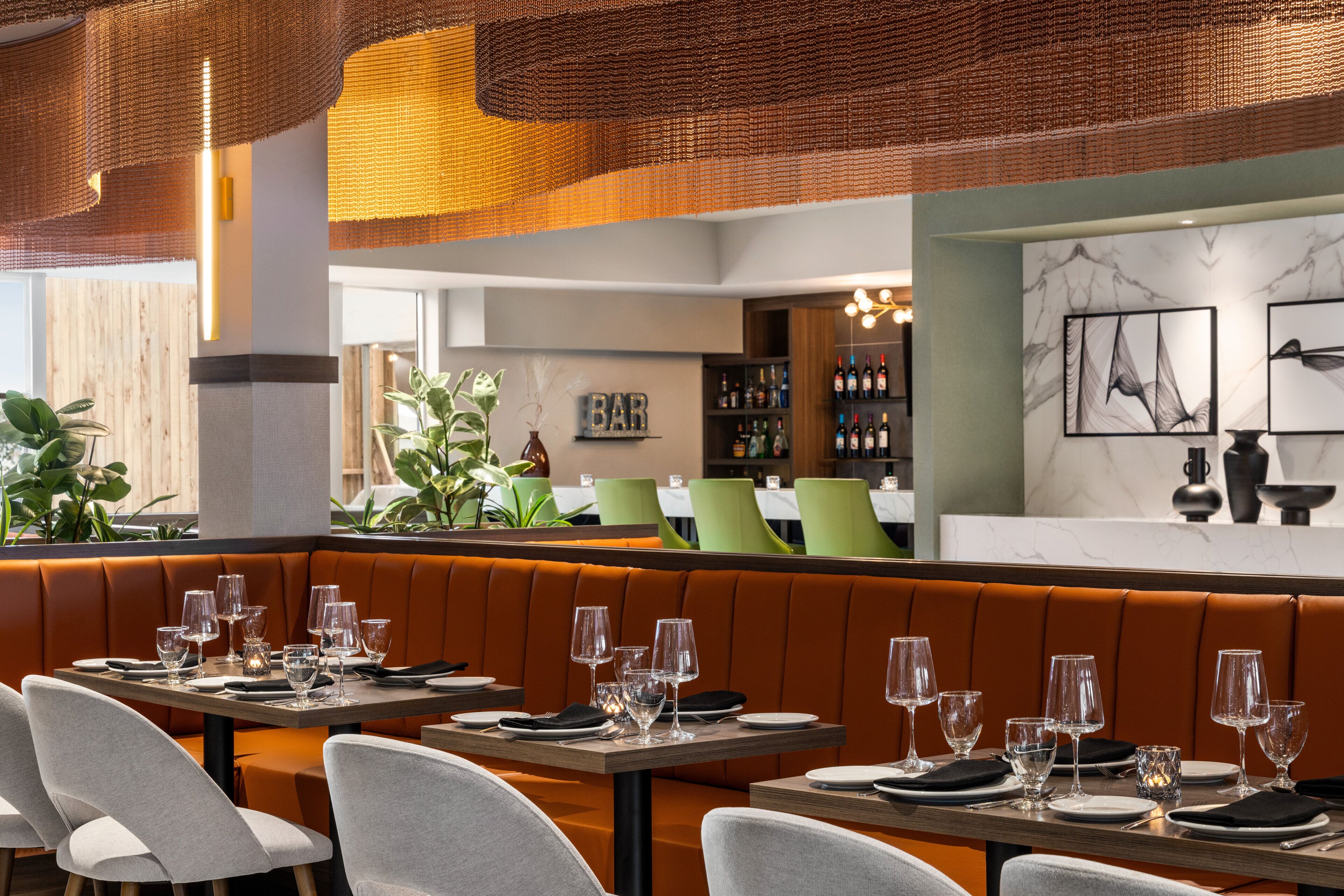 En restaurang med avskilda sittplatser i bås, en bardisk och en vägg med inramade konstverk.