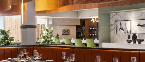 En restaurang med avskilda sittplatser i bås, en bardisk och en vägg med inramade konstverk.
