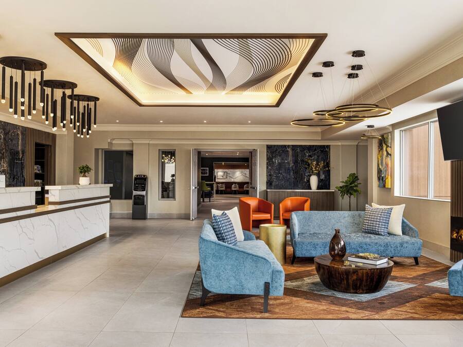 A spacious living area with a marble reception desk, modern lighting fixtures, and a fireplace.