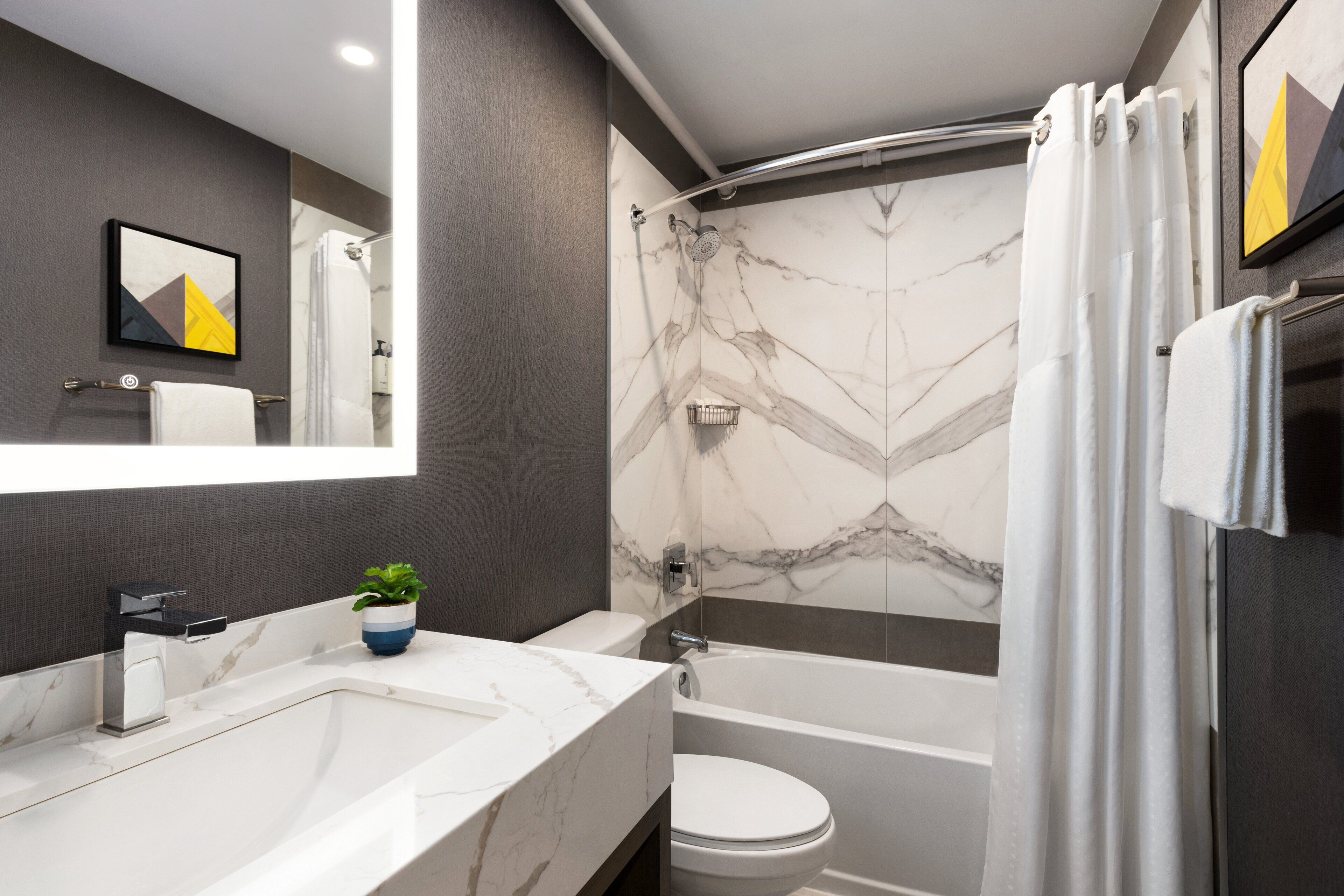 A modern bathroom with a marble sink, a toilet, and a bathtub.