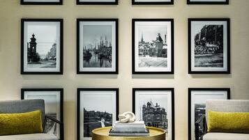Une pièce dont un mur est recouvert d’une collection de photographies en noir et blanc, encadrées, représentant différents paysages urbains et monuments emblématiques.