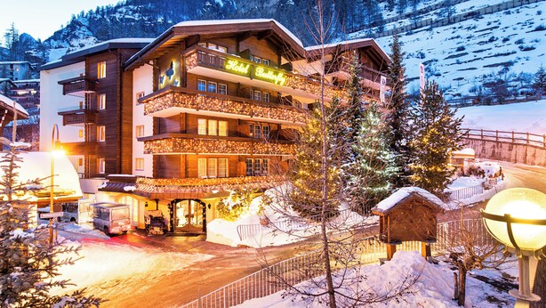 A multi-story hotel with balconies and a lit sign reading "Hotel Butterfly." - Hotel Butterfly (Zermatt)