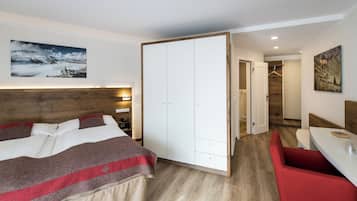 A bedroom with a bed, a wardrobe, a red bench, and a painting on the wall.