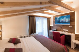 Una habitación de hotel moderna con una cama grande, un escritorio y un televisor montado mostrando el pronóstico del tiempo.
