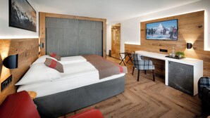 A modern hotel room with a bed, a desk, and a TV mounted on the wall. - Hotel Butterfly (Zermatt)