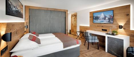 A modern hotel room with a bed, a desk, and a TV mounted on the wall.
