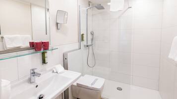 A modern bathroom with a glass shelf, a sink, a toilet, and a shower.
