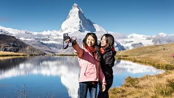 Zwei Personen machen ein Selfie mit Bergen im Hintergrund.