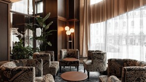 Un interior moderno con mobiliario estampado, una mesa redonda y ventanas amplias que ofrecen vistas a edificios.