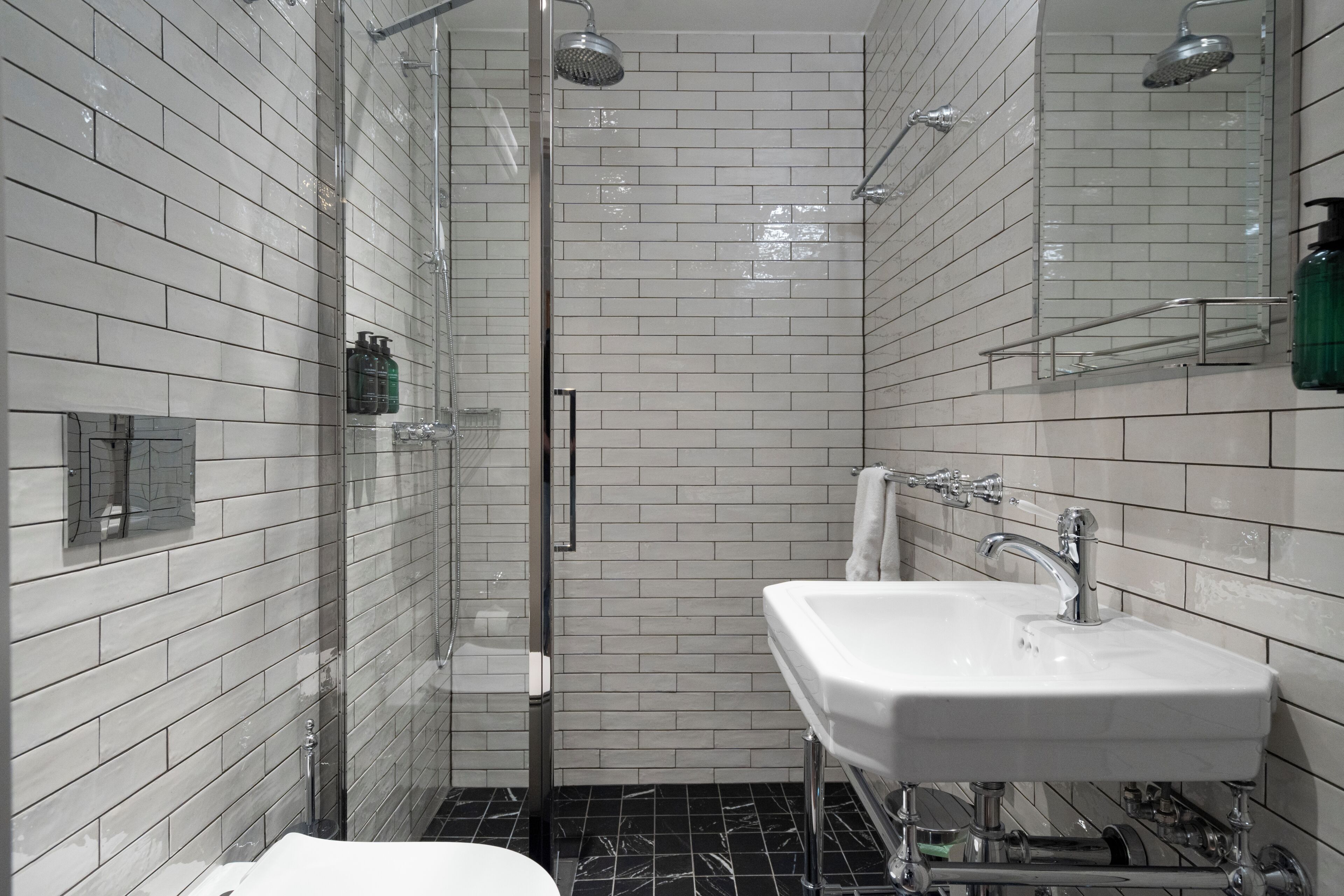 A modern bathroom with a glass-enclosed shower, a white sink, and tiled walls.