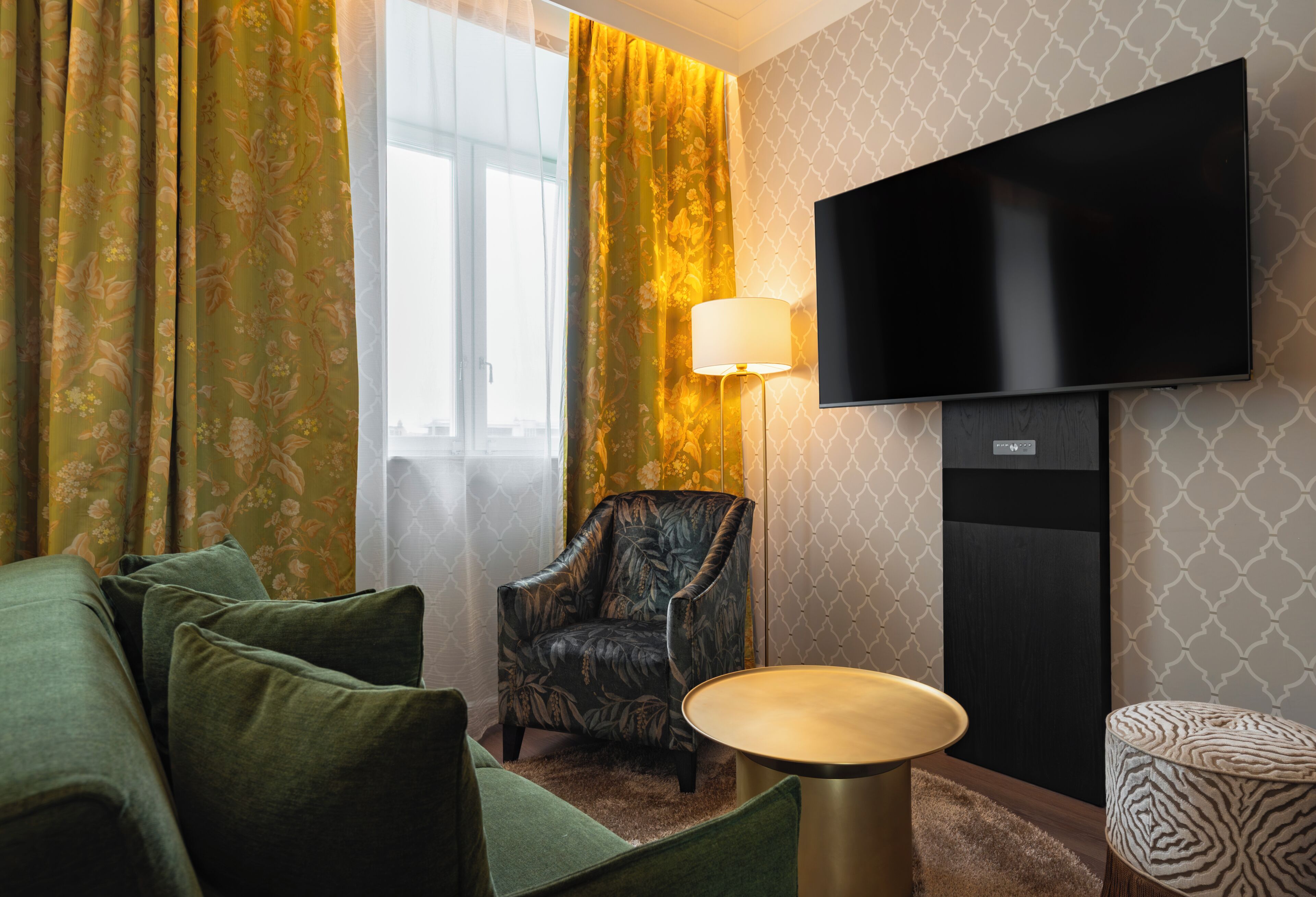 A room with a sofa, a chair, a TV, and a lamp.