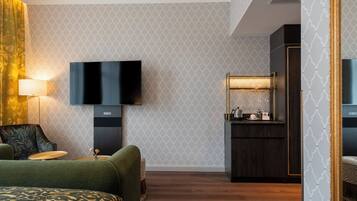 A hotel room with a bed, a TV, a desk, and a small kitchenette.