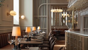 Un restaurante con mesas largas, sillas y copas de vino colgantes.