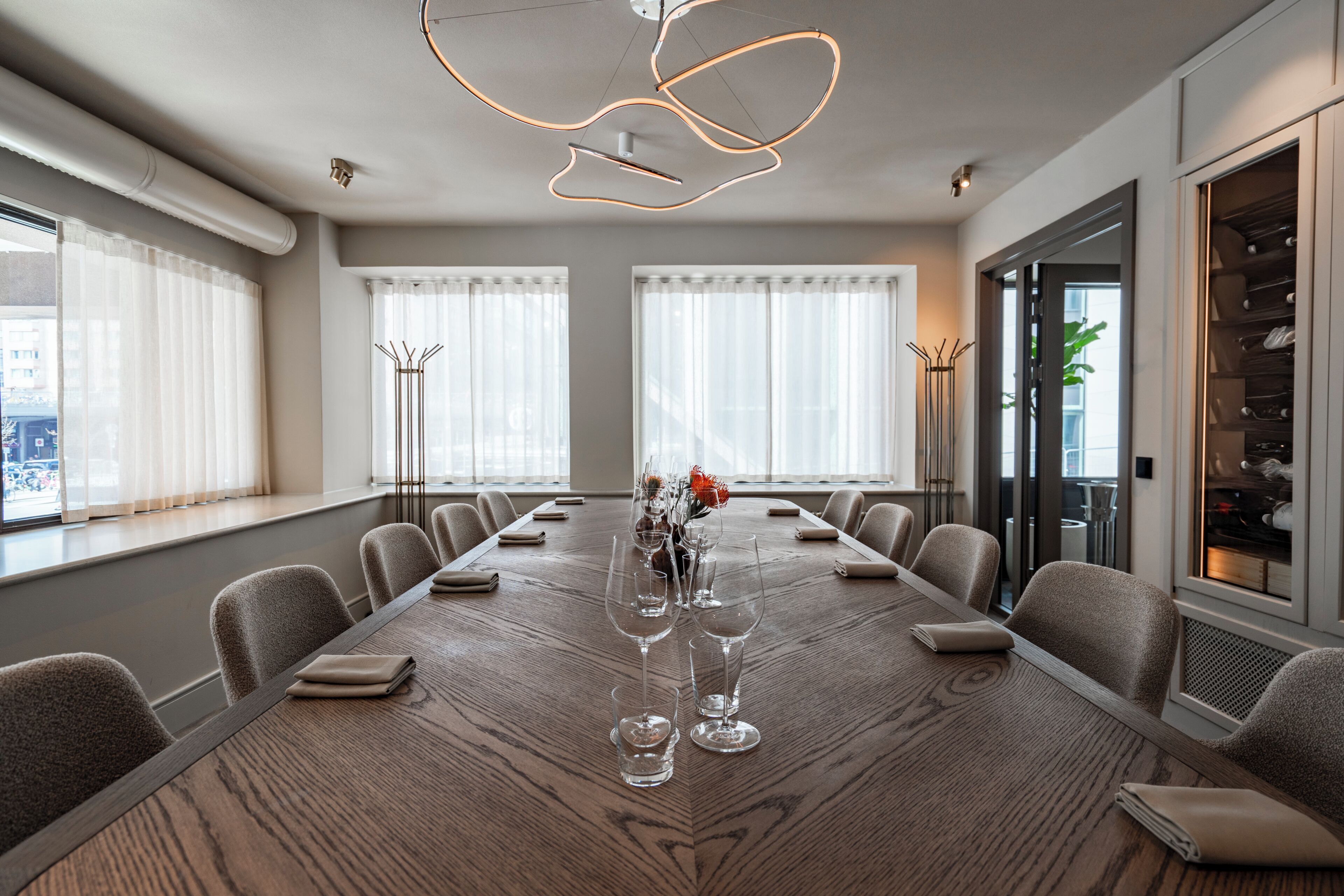 Una sala conferenze con un lungo tavolo, sedie e un lampadario moderno.