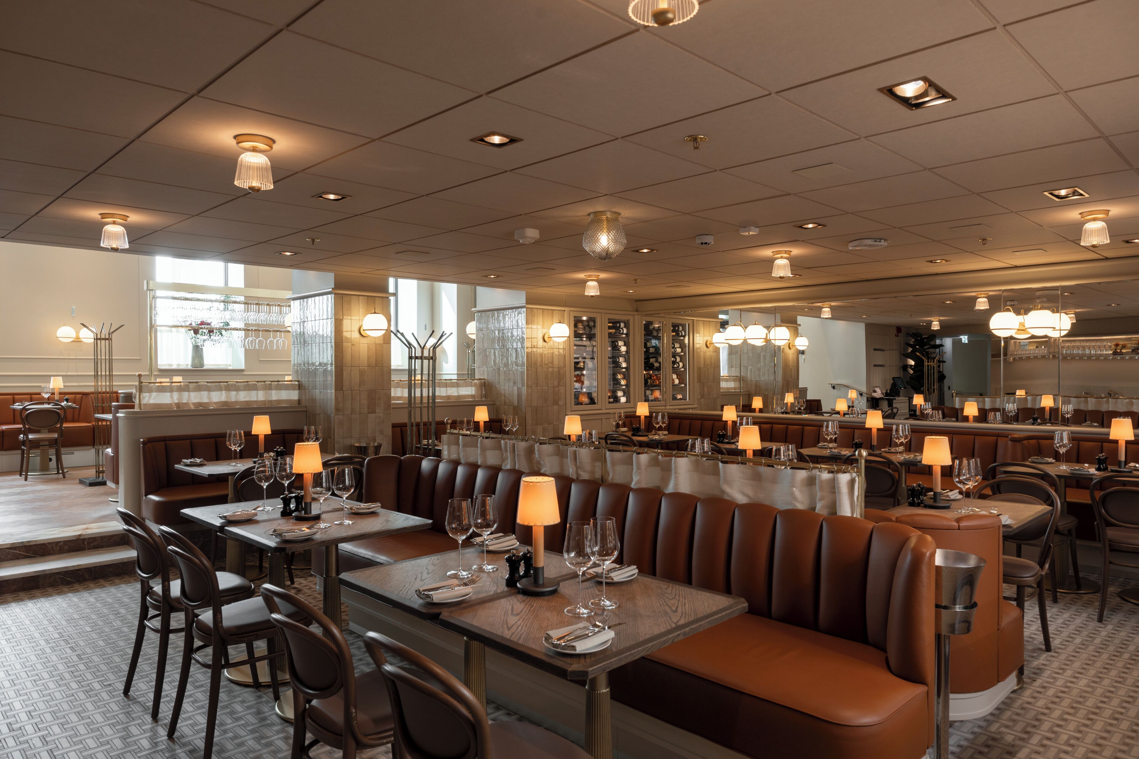 En restaurang med avskilda bås, bord och en bardisk.