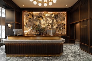 A reception desk with a geometric patterned wall, a marble floor, and a lamp. - Thon Hotel Vasa (Stockholm)