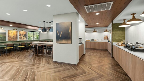 Una cocina moderna con piso de madera, iluminación colgante y una isla central.