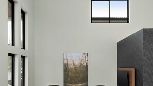Un interior moderno con dos sillones verdes, un ventanal grande y una obra de arte enmarcada en la pared.