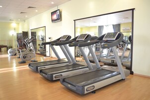 A gym with treadmills, exercise bikes, and mirrors.
