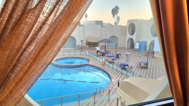 Vista d'una zona de piscines amb diverses piscines, gandules i una zona de seients coberta.