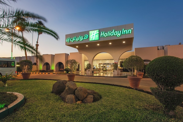 A Holiday Inn hotel with a modern facade, arched entrance, and well-maintained landscaping.