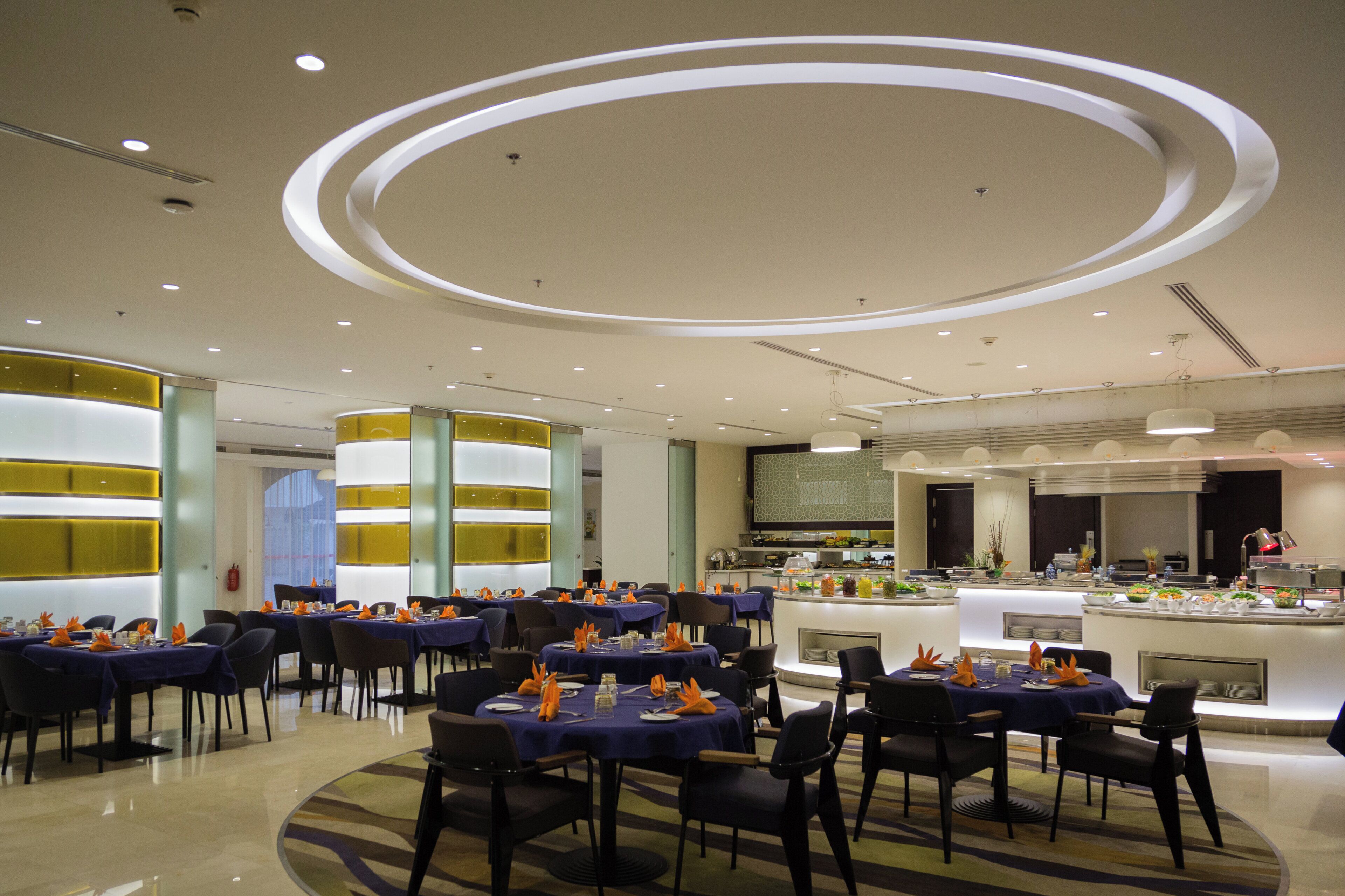 Un espace repas moderne avec des tables rondes, des chaises et un comptoir de buffet.