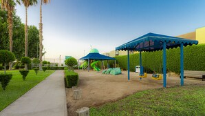 Un parc infantil amb cadira d'oscil·lació, tobogan i zona coberta.