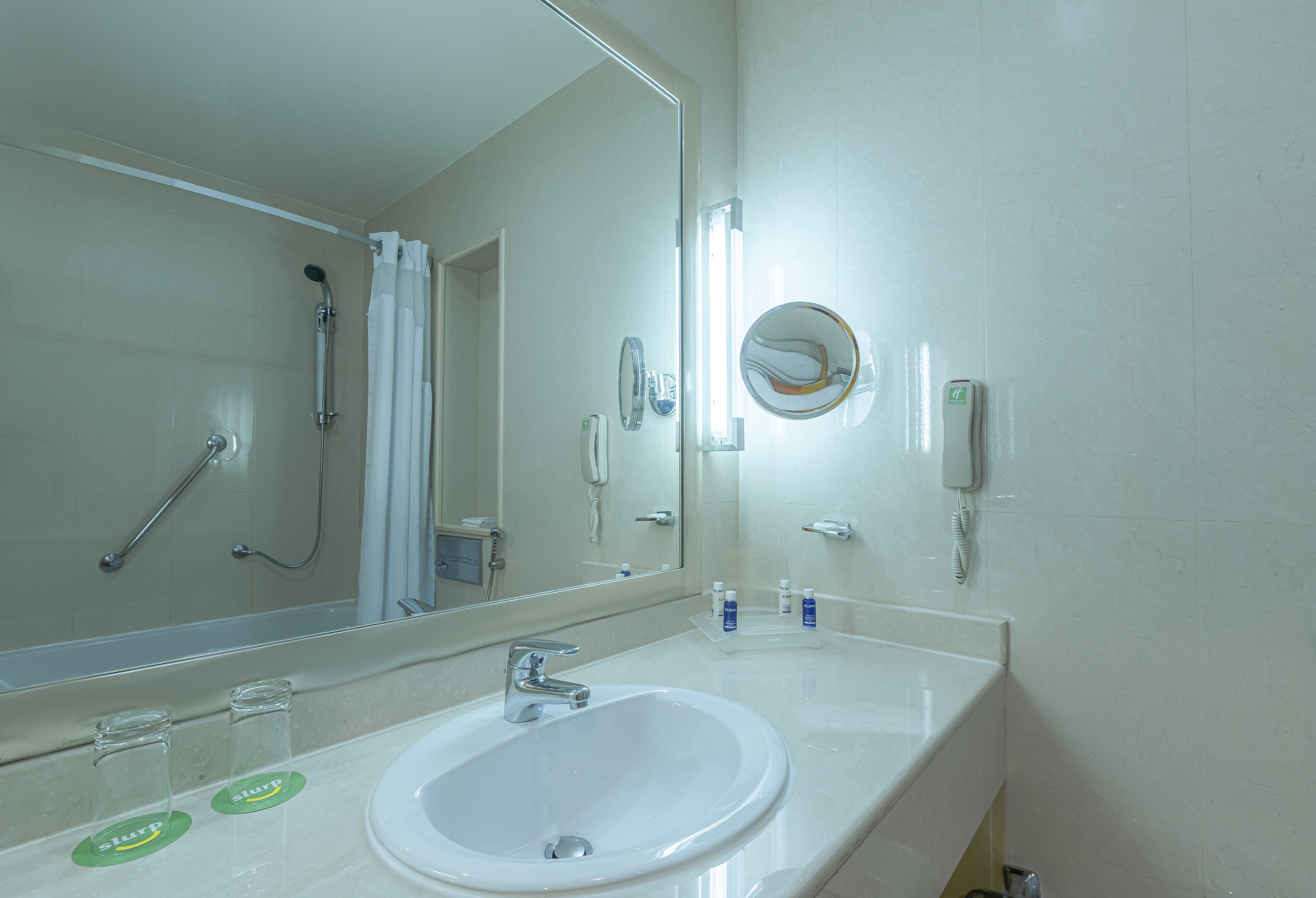A bathroom with a white sink, a mirror, a shower, and a toilet.