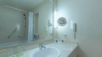 A bathroom with a white sink, a mirror, a shower, and a toilet.