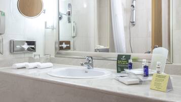 A hotel bathroom with a sink, mirror, and toiletries.
