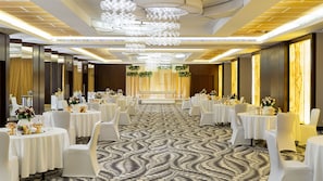 A banquet hall with round tables, white chairs, and a patterned carpet. - Holiday Inn Yanbu by IHG (Yanbu)