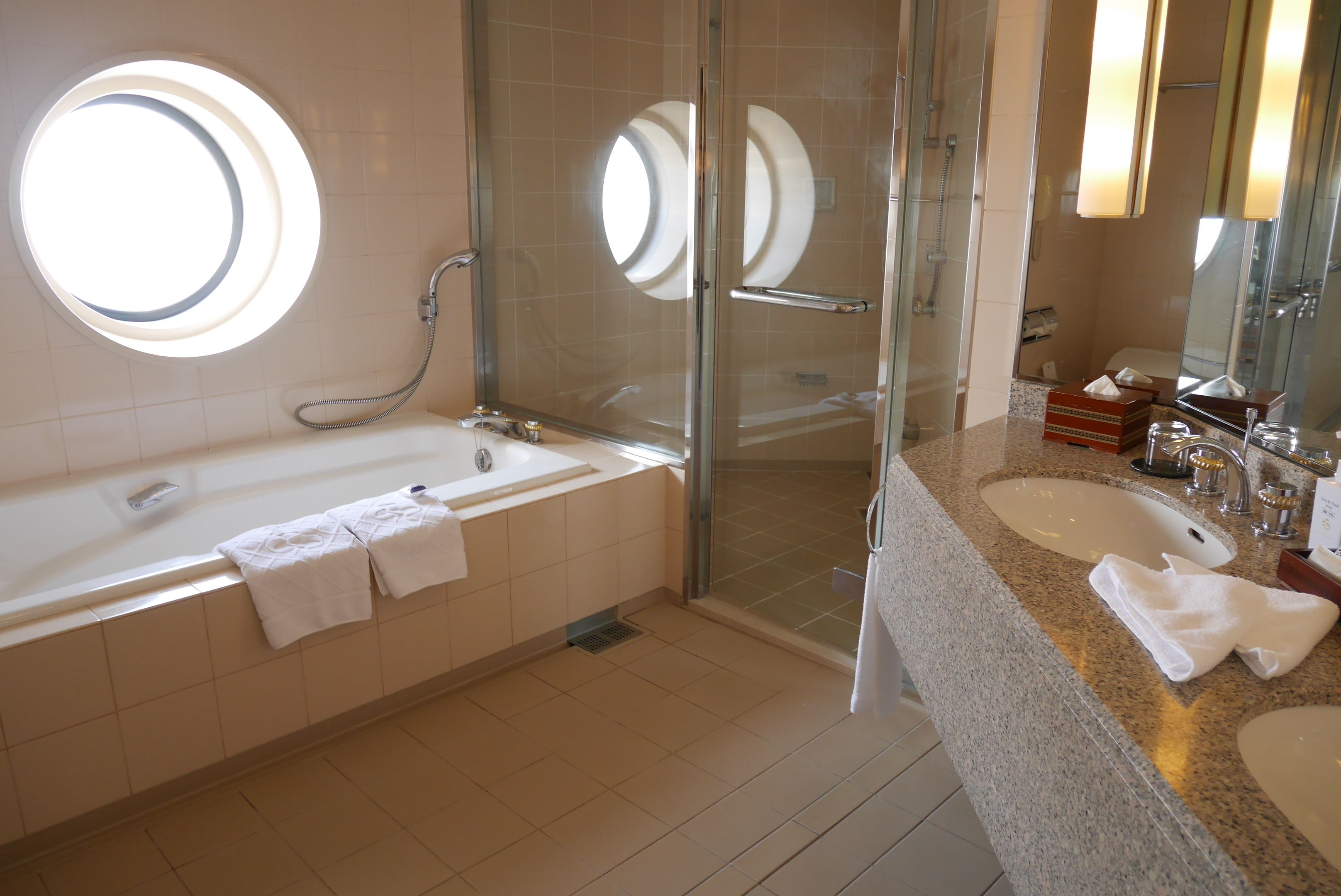 A modern bathroom with a bathtub, a glass-enclosed shower, and a vanity with a sink and mirror.