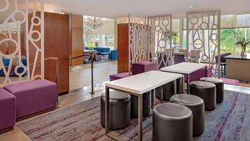 A modern hotel lobby with a seating area, a reception desk, and a view of the outdoors.