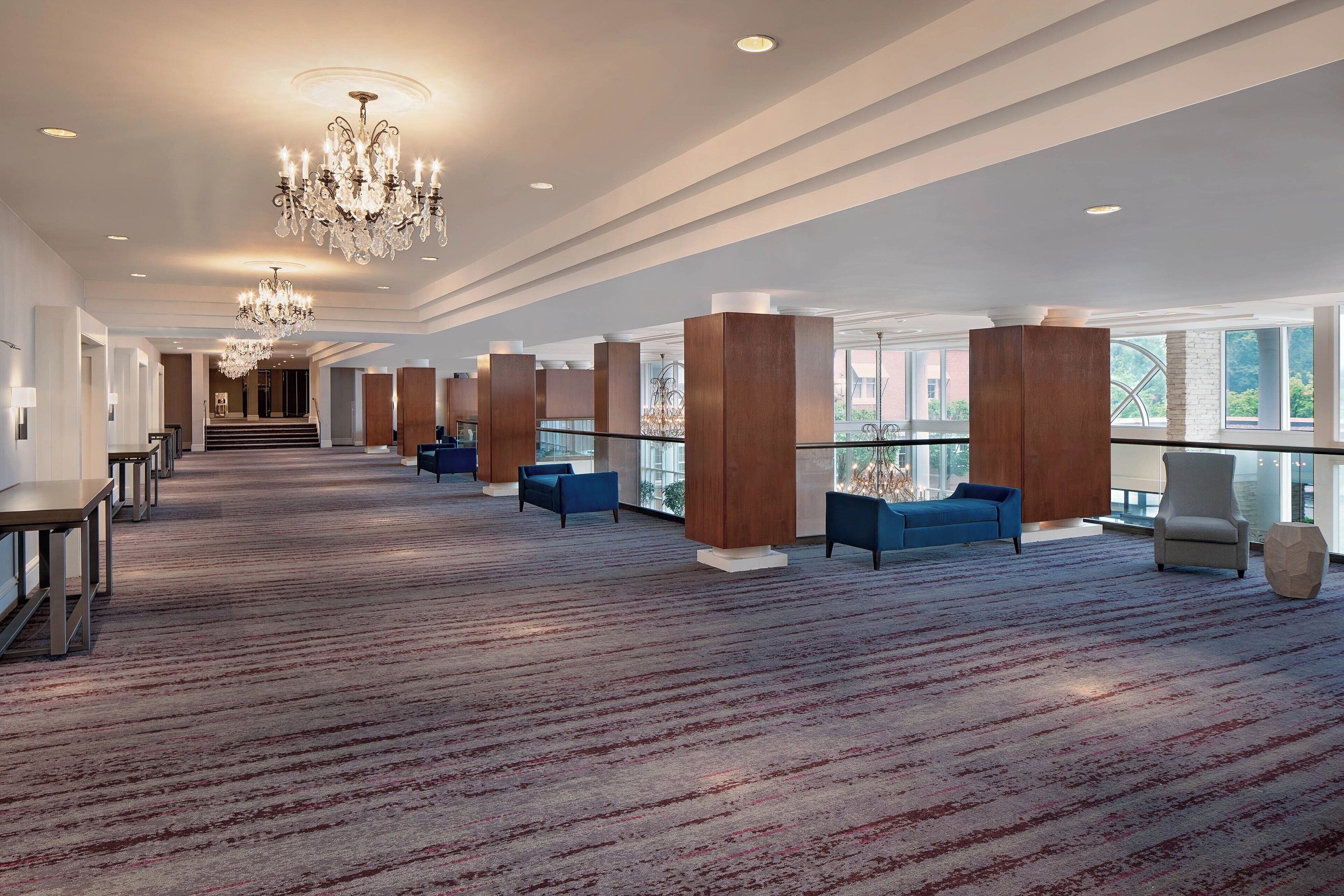 A spacious lobby with a patterned carpet, seating areas, and a grand chandelier.
