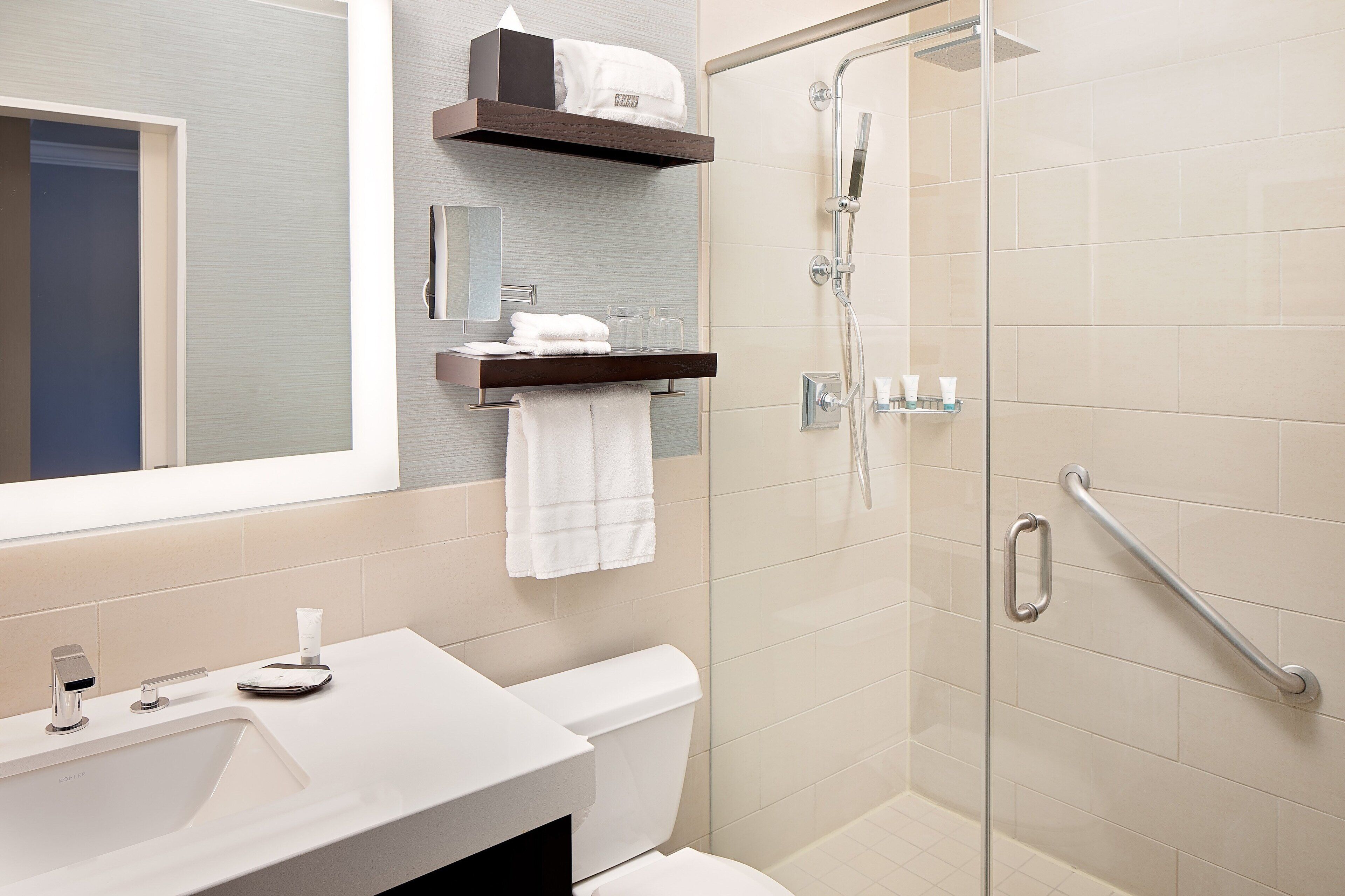 A modern bathroom with a glass-enclosed shower, a white sink, and a towel rack.