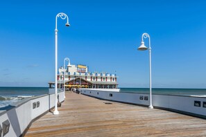 A pier with a wooden walkway leading to a building with multiple levels and balconies, featuring a sign that reads "CAESARS SHACK." - Comfort Inn & Suites Daytona Beach Oceanfront (Daytona Beach)