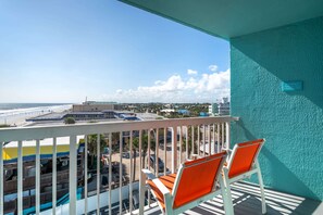A balcony with two orange chairs, a view of the beach, and a sign indicating a restaurant. - Comfort Inn & Suites Daytona Beach Oceanfront (Daytona Beach)