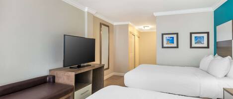 A hotel room with a bed, a TV, a bench, and two framed pictures on the wall.