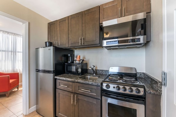 A modern kitchen with stainless steel appliances, dark wooden cabinets, and a granite countertop.