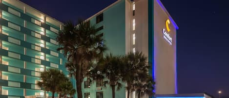Un hotel con un llamativo letrero de 'Comfort Inn & Suites', varios pisos y un área de estacionamiento.