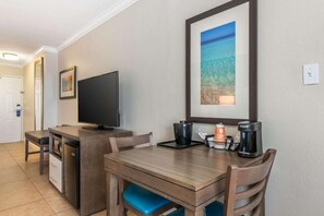 A compact hotel room with a kitchenette, a flat-screen TV, a framed landscape picture, and a coffee maker on the counter. - Comfort Inn & Suites Daytona Beach Oceanfront (Daytona Beach)