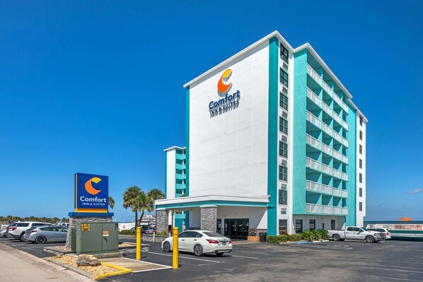A Comfort Inn & Suites hotel with a prominent sign, a parking lot, and a clear blue sky. - Comfort Inn & Suites Daytona Beach Oceanfront (Daytona Beach)