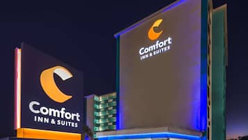 A Comfort Inn & Suites sign with illuminated branding, a modern building facade, and a visible address number.