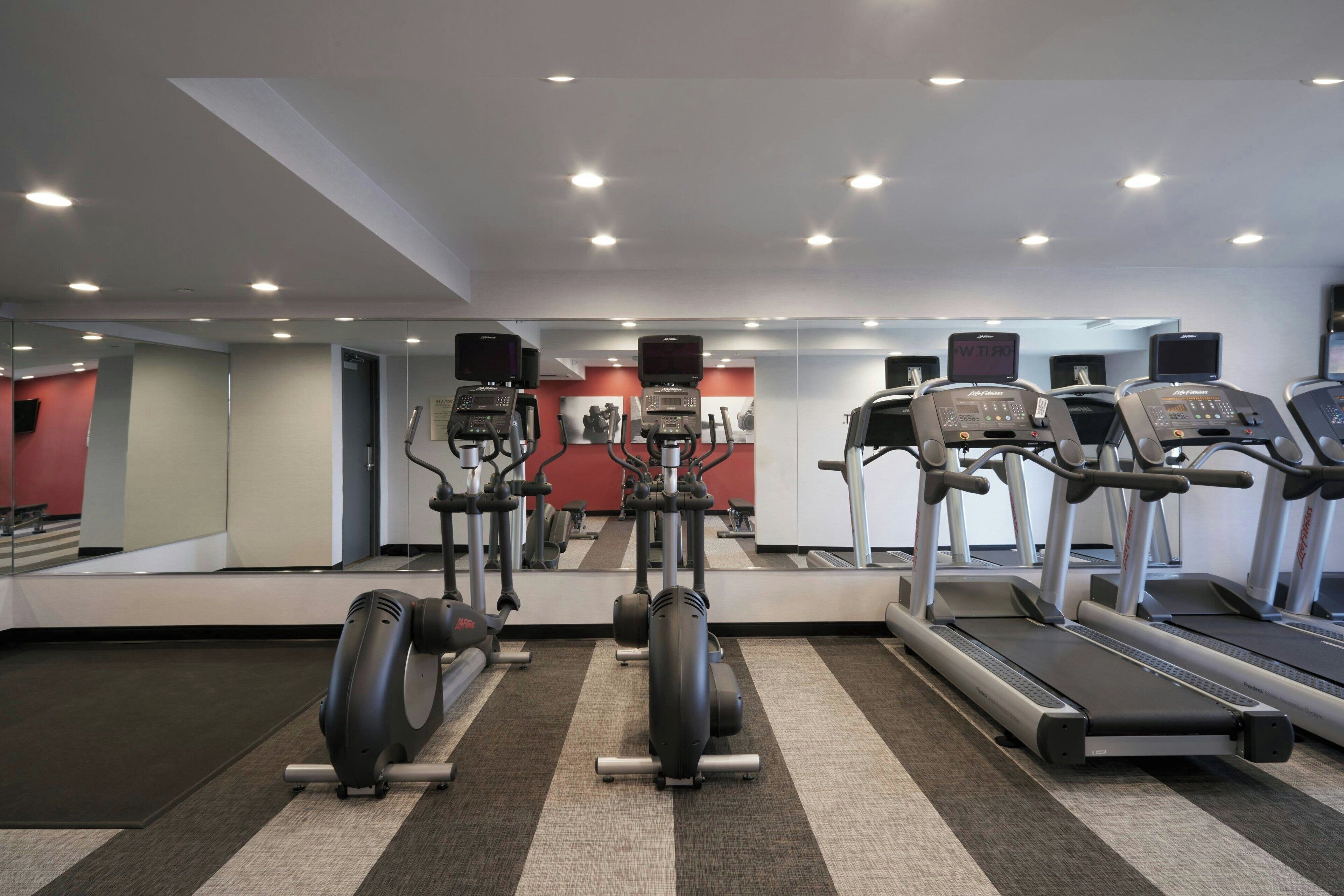 A gym with treadmills, elliptical machines, and weight equipment.